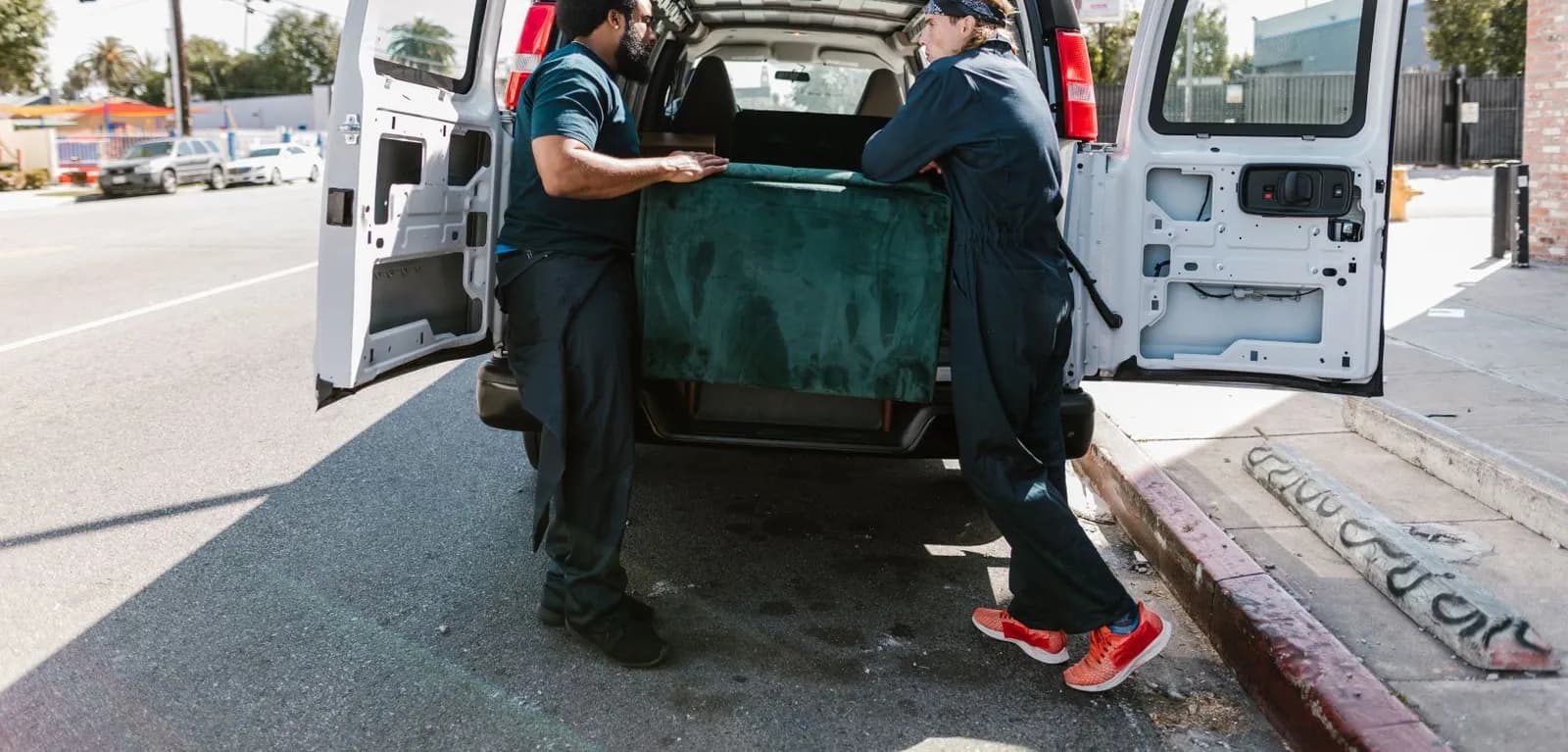 Two movers loading a sofa into the back of a van