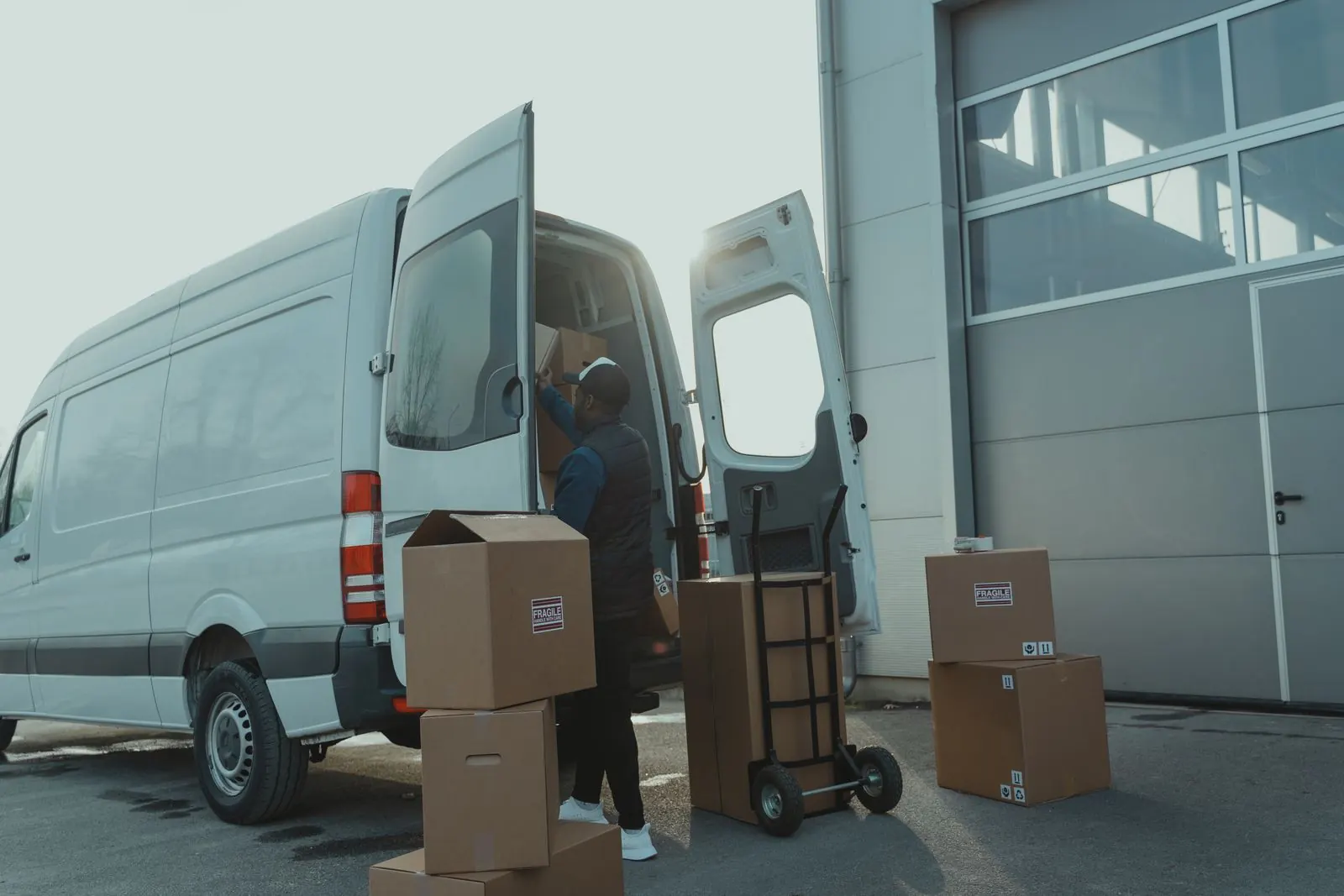 Courier loading an open van outside a warehouse
