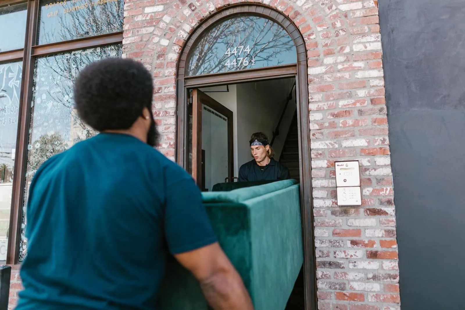 Two-person team carrying a sofa into a home